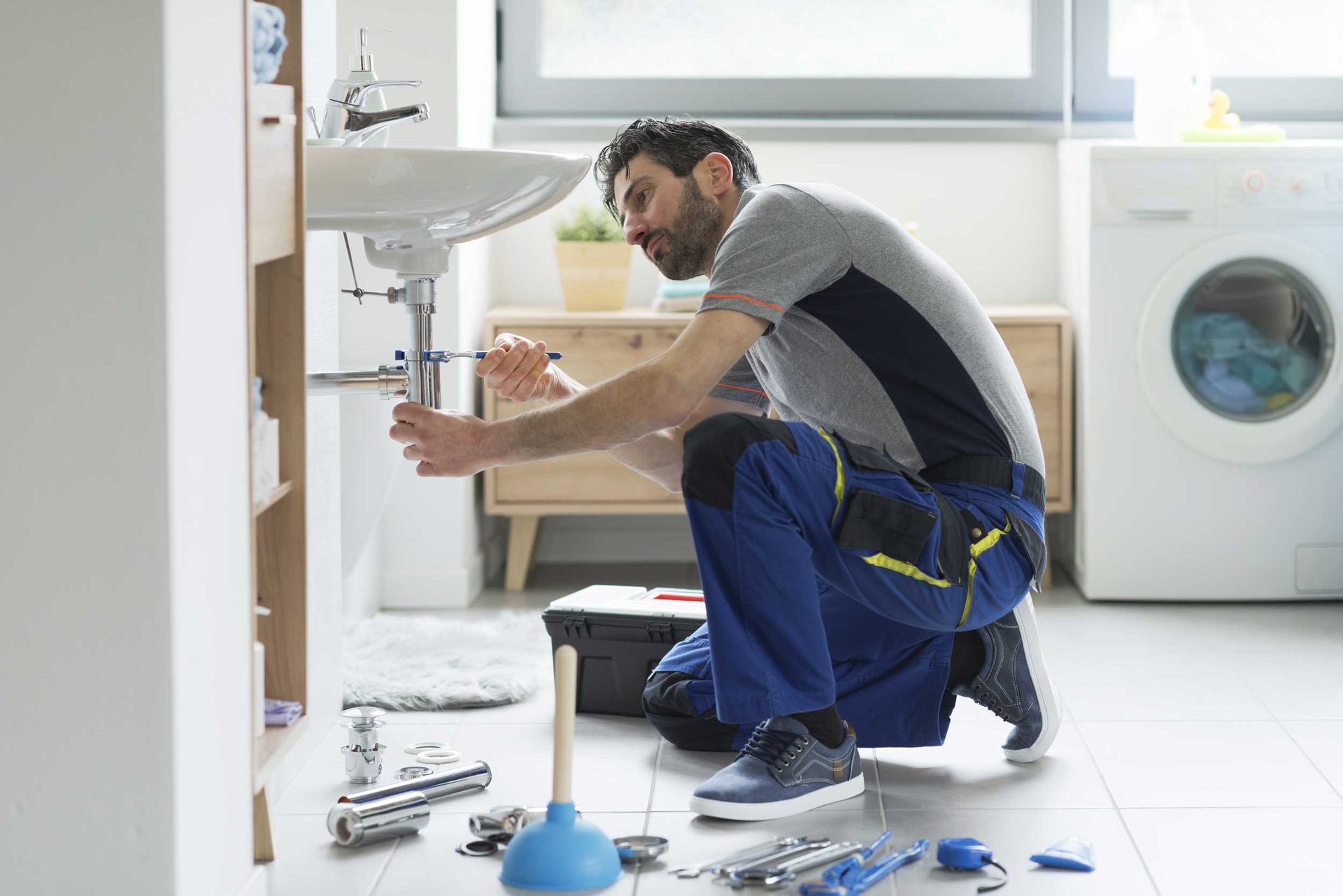 Plumbing installation contractor working on a bathroom sink in a home.