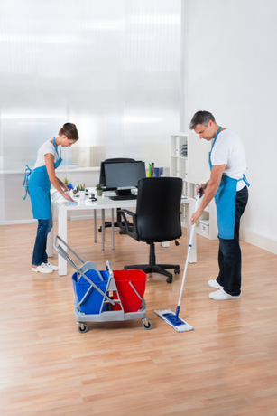 A man and a woman are cleaning an office with a mop.