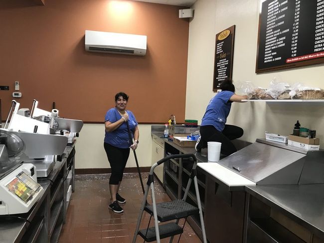 Two women are cleaning a kitchen in a restaurant.