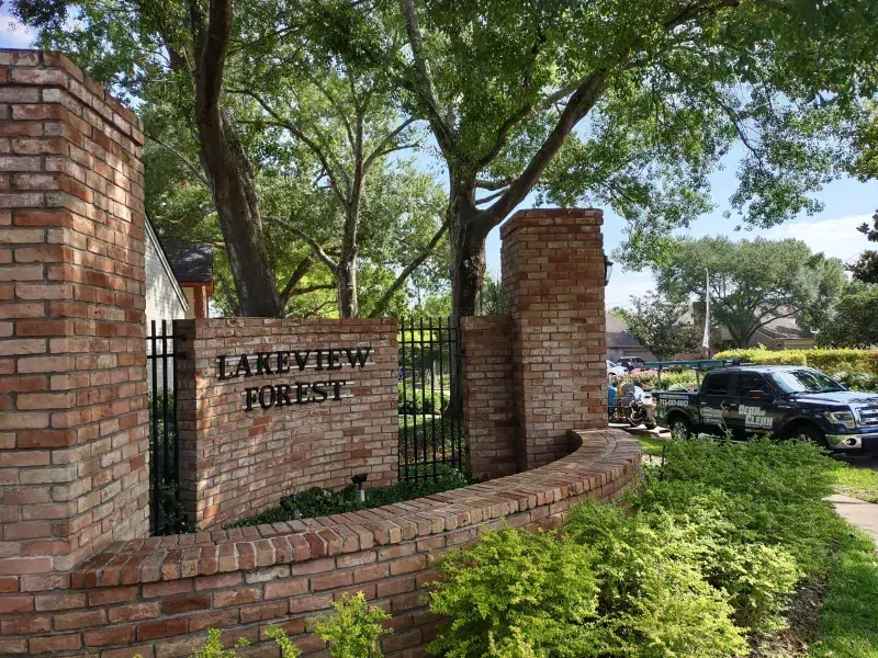 Brick entrance to Lakeview Forest neighborhood with green shrubbery and trees.
