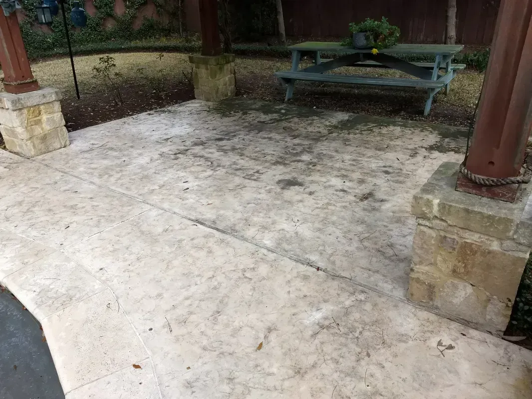 Patio with stained concrete, wooden posts, and a picnic table in the background.