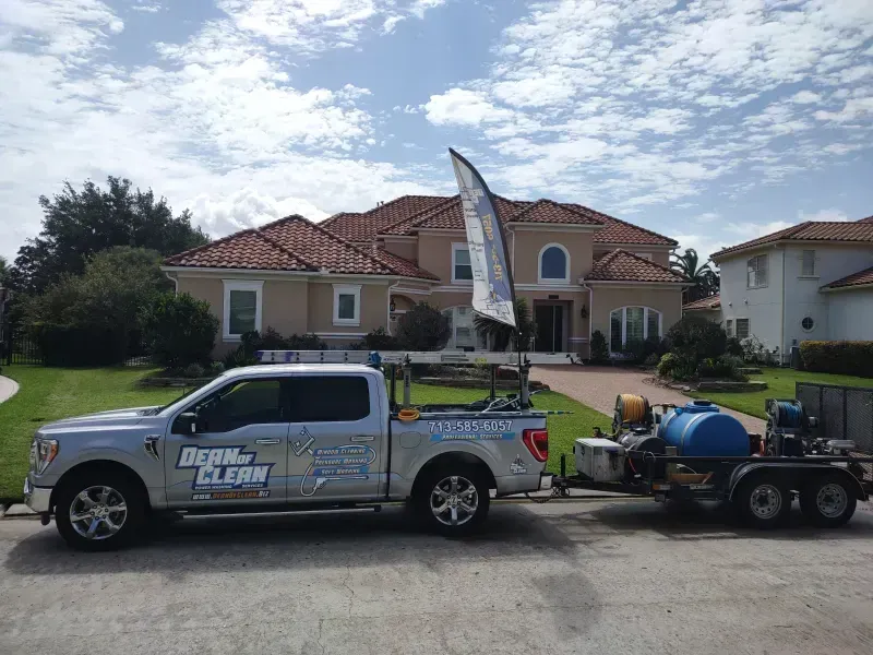 Silver truck with trailer in front of a house, advertising Dean 4 Clean. Blue water tank on trailer.