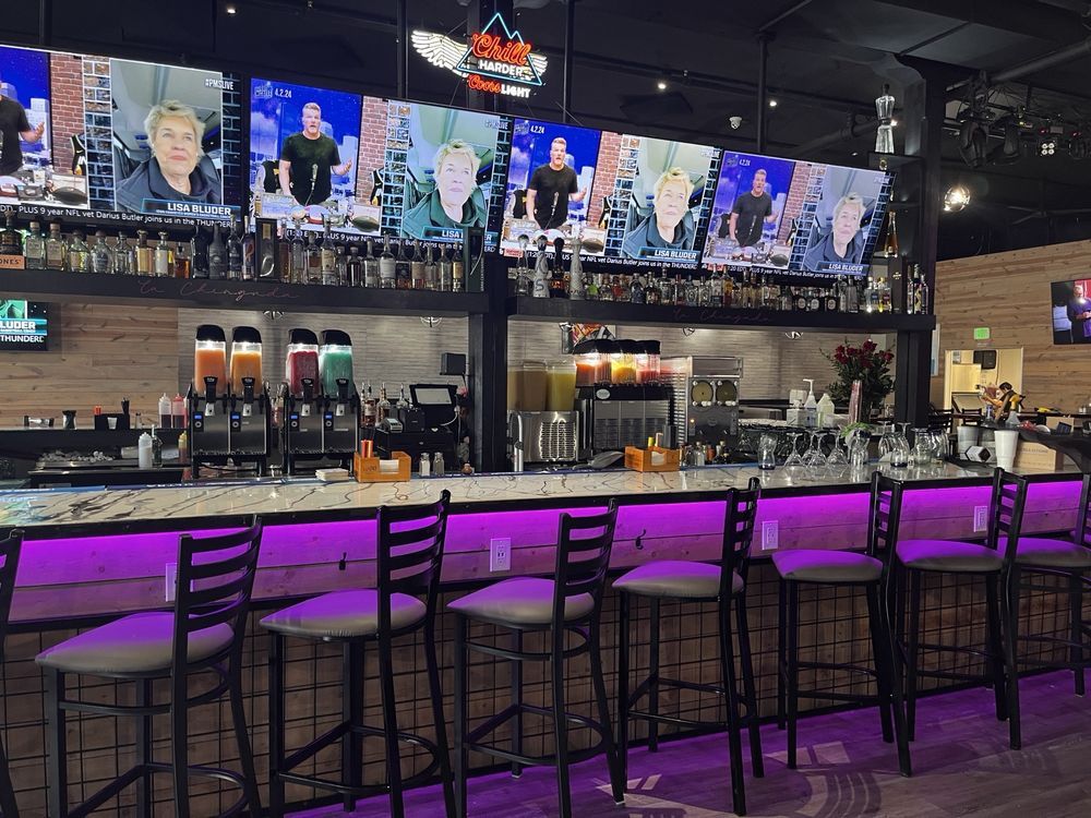 Empty modern bar with purple-lit counter, high stools, TVs, and beer taps behind the bar. Empty modern bar with purple-lit counter, high stools, TVs, and beer taps behind the bar.