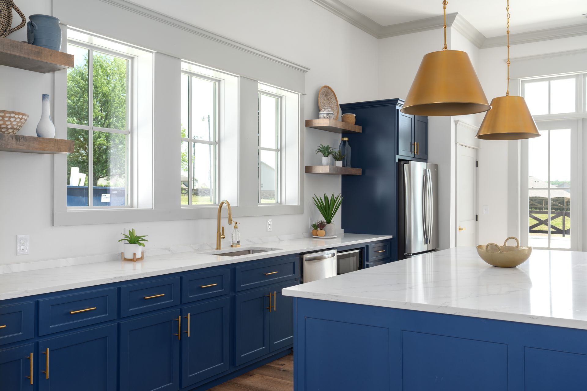 a kitchen with blue cabinets , white counter tops , stainless steel appliances , and a large island .