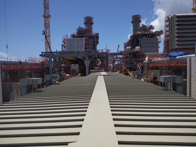 Construction site with power plant, cranes, and blue sky.