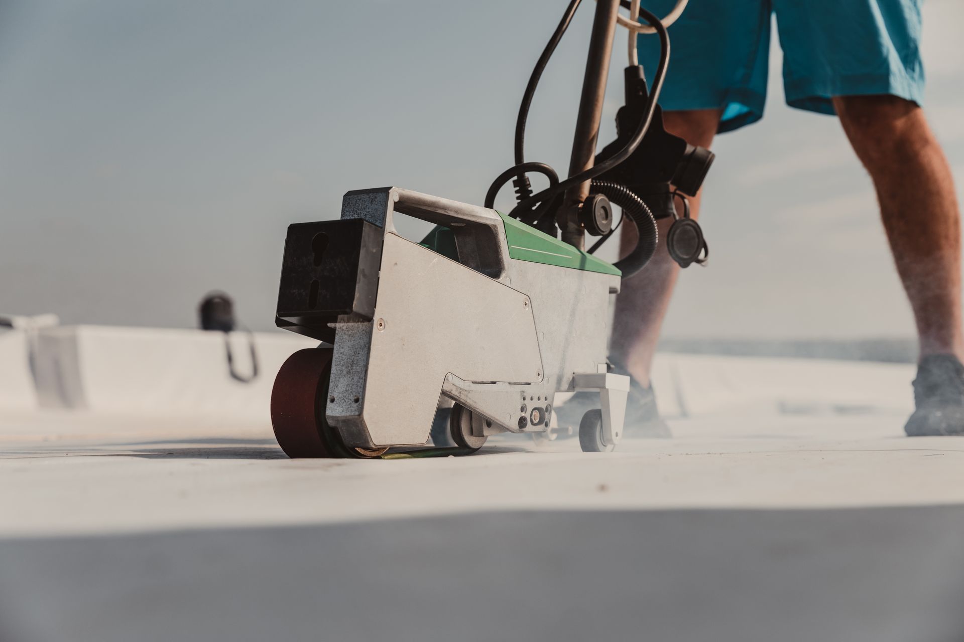 A man is using a machine to seal a roof.