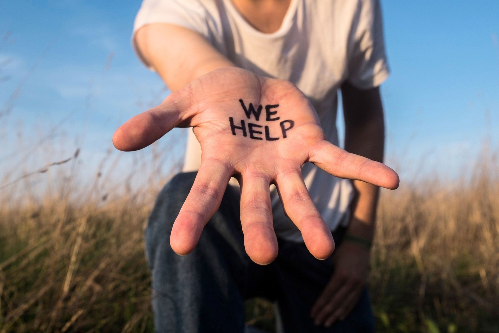Person Extending Hand With We Help Written on Palm — Lake Macquarie Counselling & Psychotherapy In Cardiff, NSW