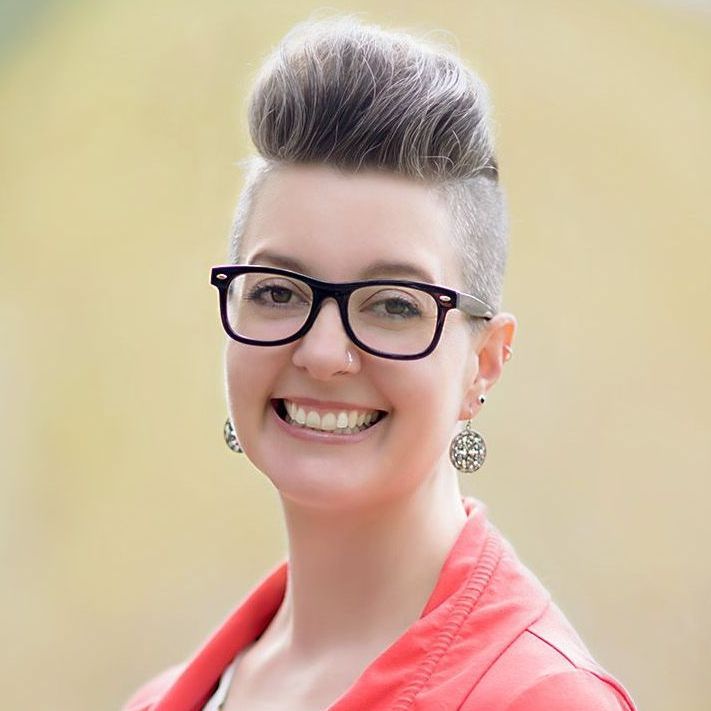 A woman wearing glasses and earrings is smiling for the camera.
