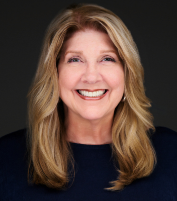 A woman wearing an orange jacket is smiling for the camera.