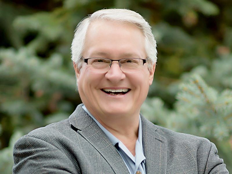 A man wearing glasses and a suit is smiling for the camera.