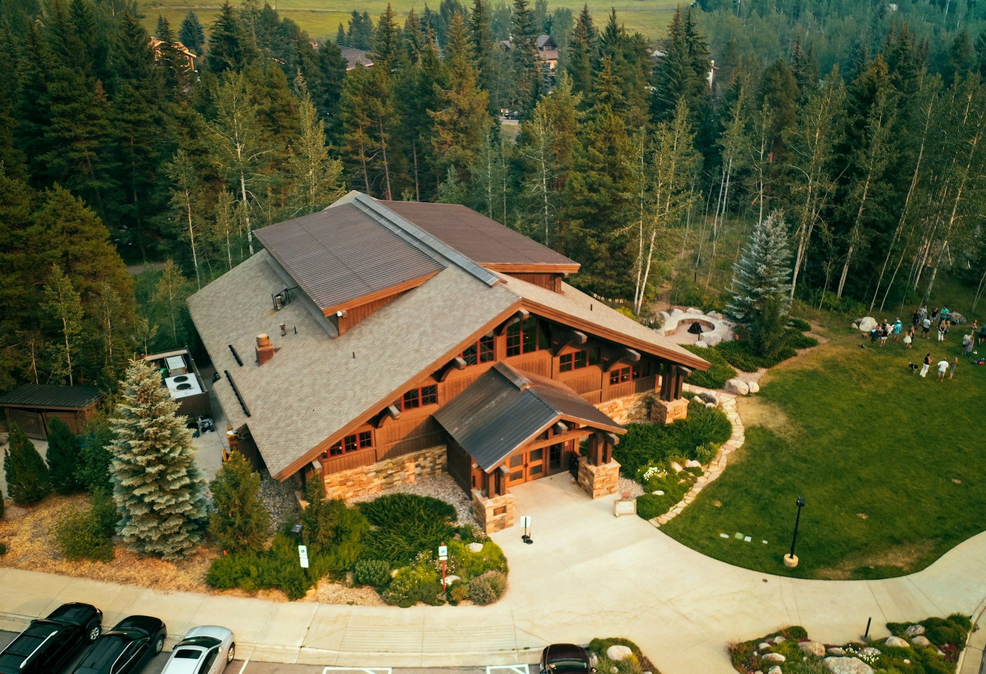 An aerial view of a large log cabin in the middle of a forest.