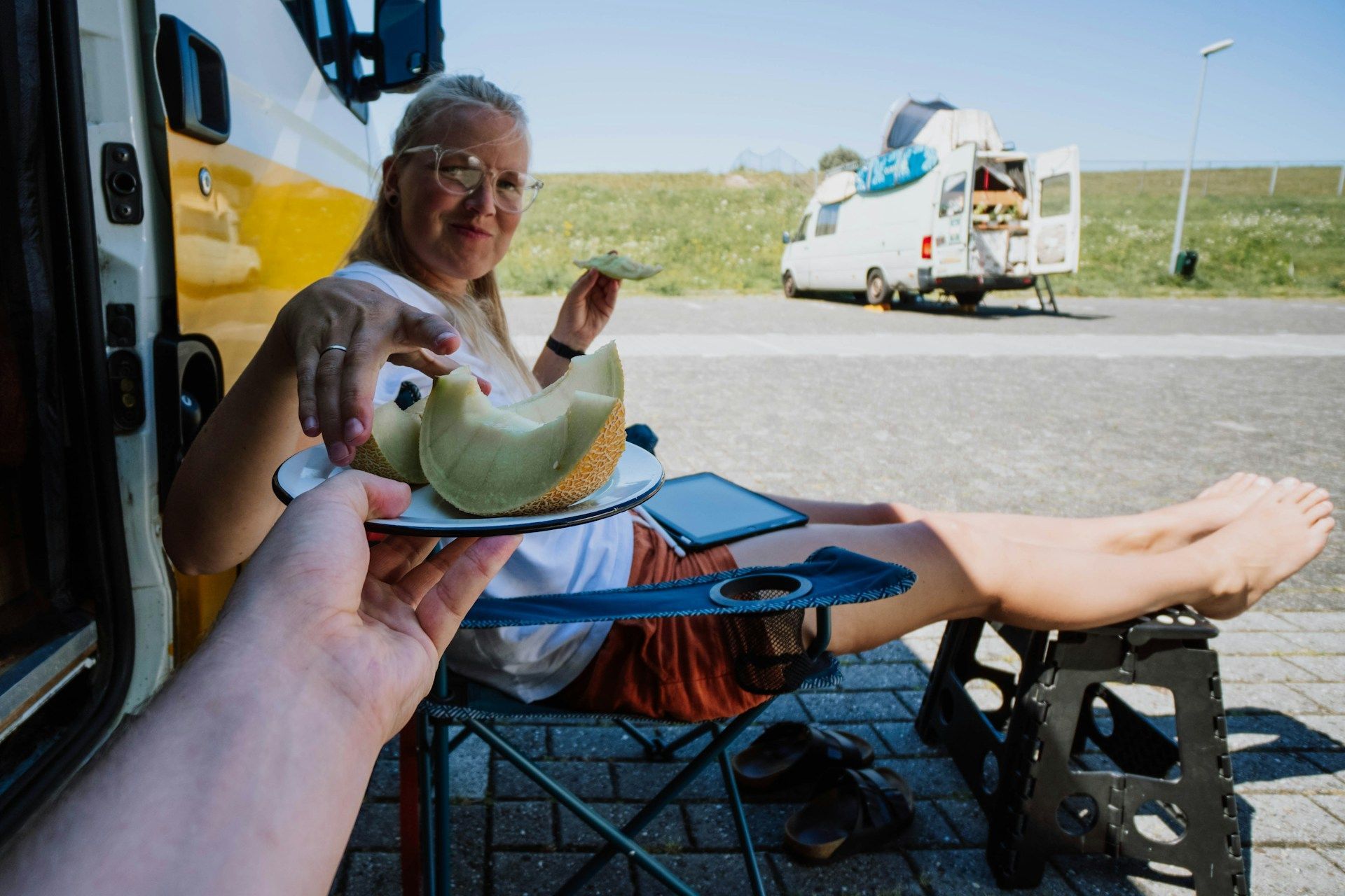 A woman is sitting in a chair eating a melon.