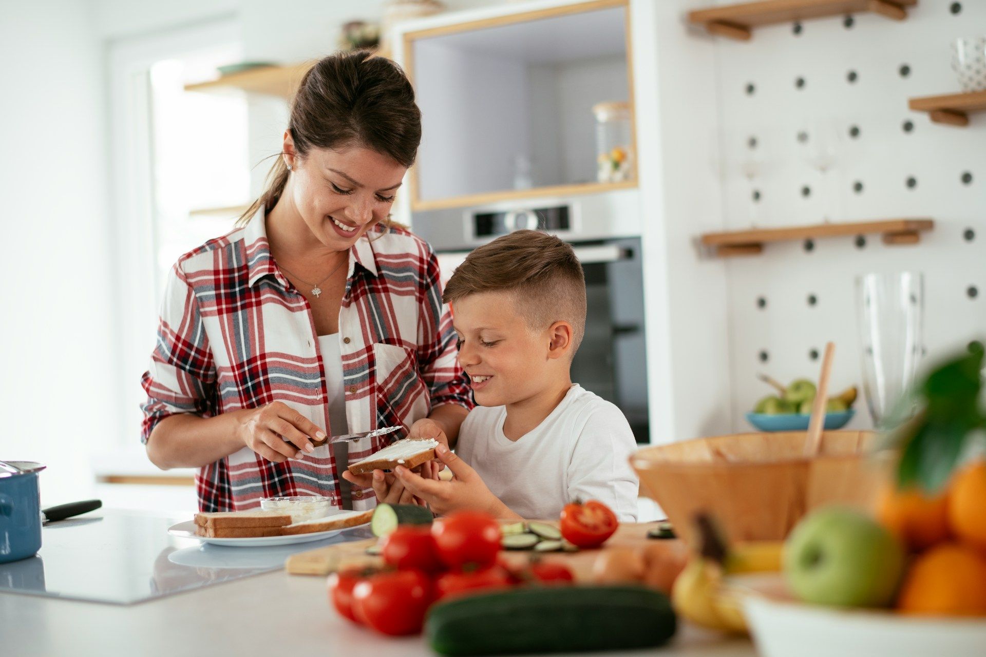 A woman and a child are making a sandwich in the kitchen.