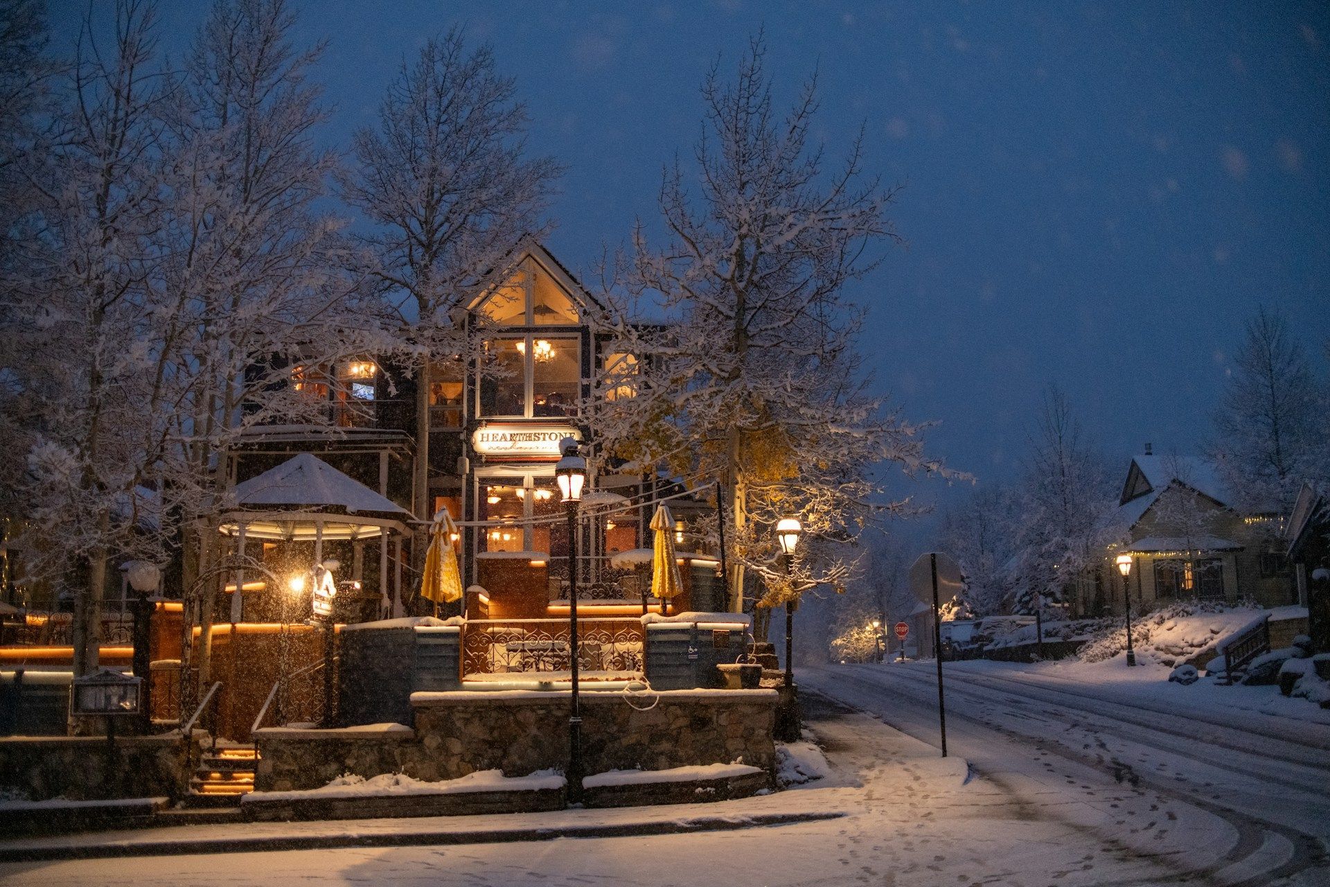 A house is lit up in the snow at night