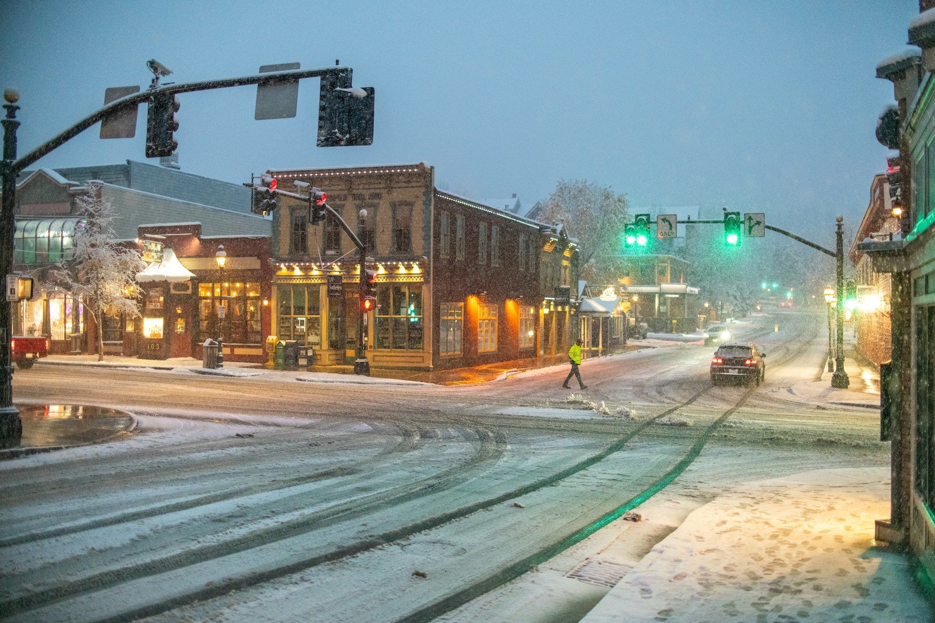 A person is crossing a snowy street in a small town.