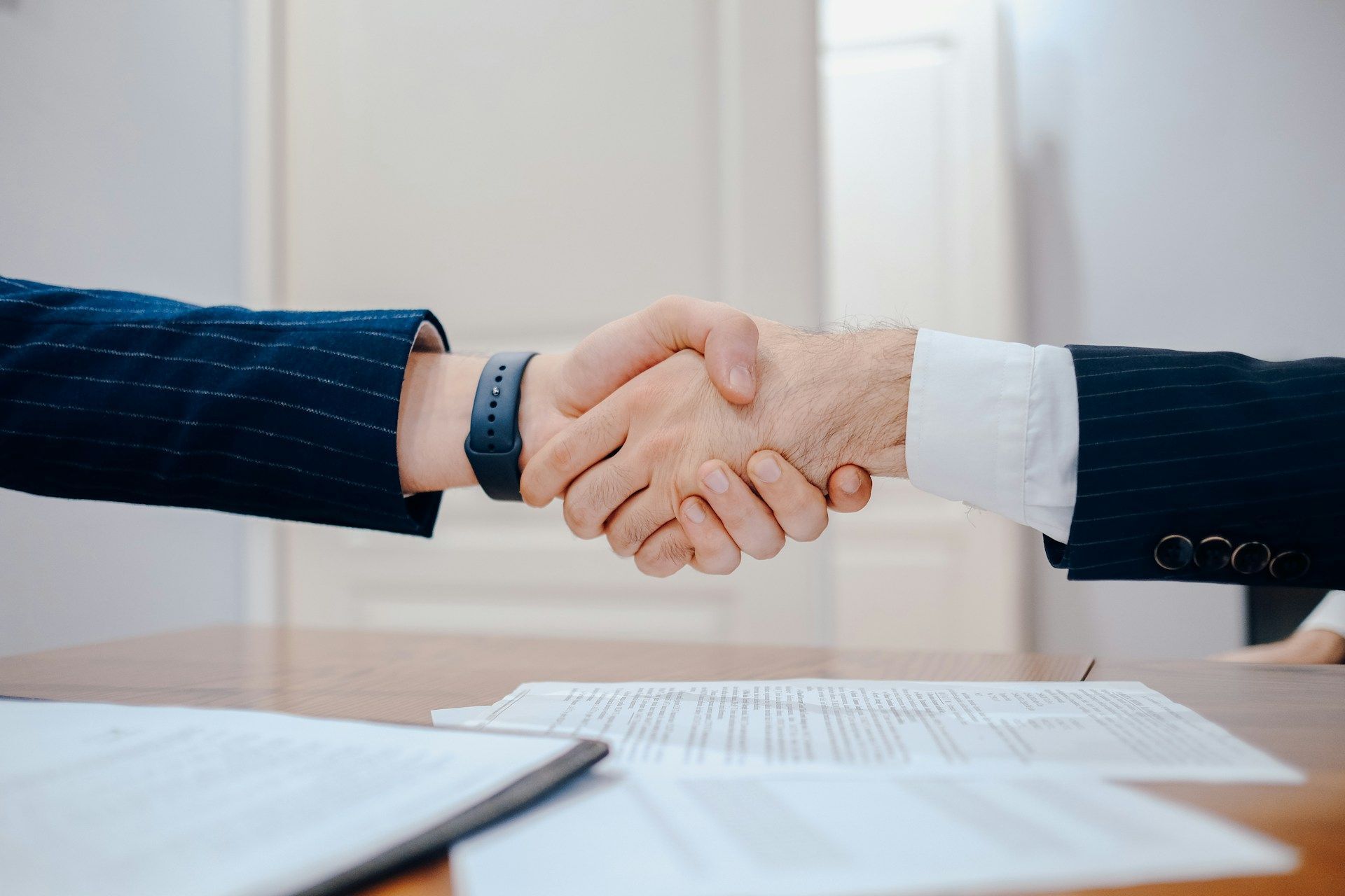 A man and a woman are shaking hands over a table.