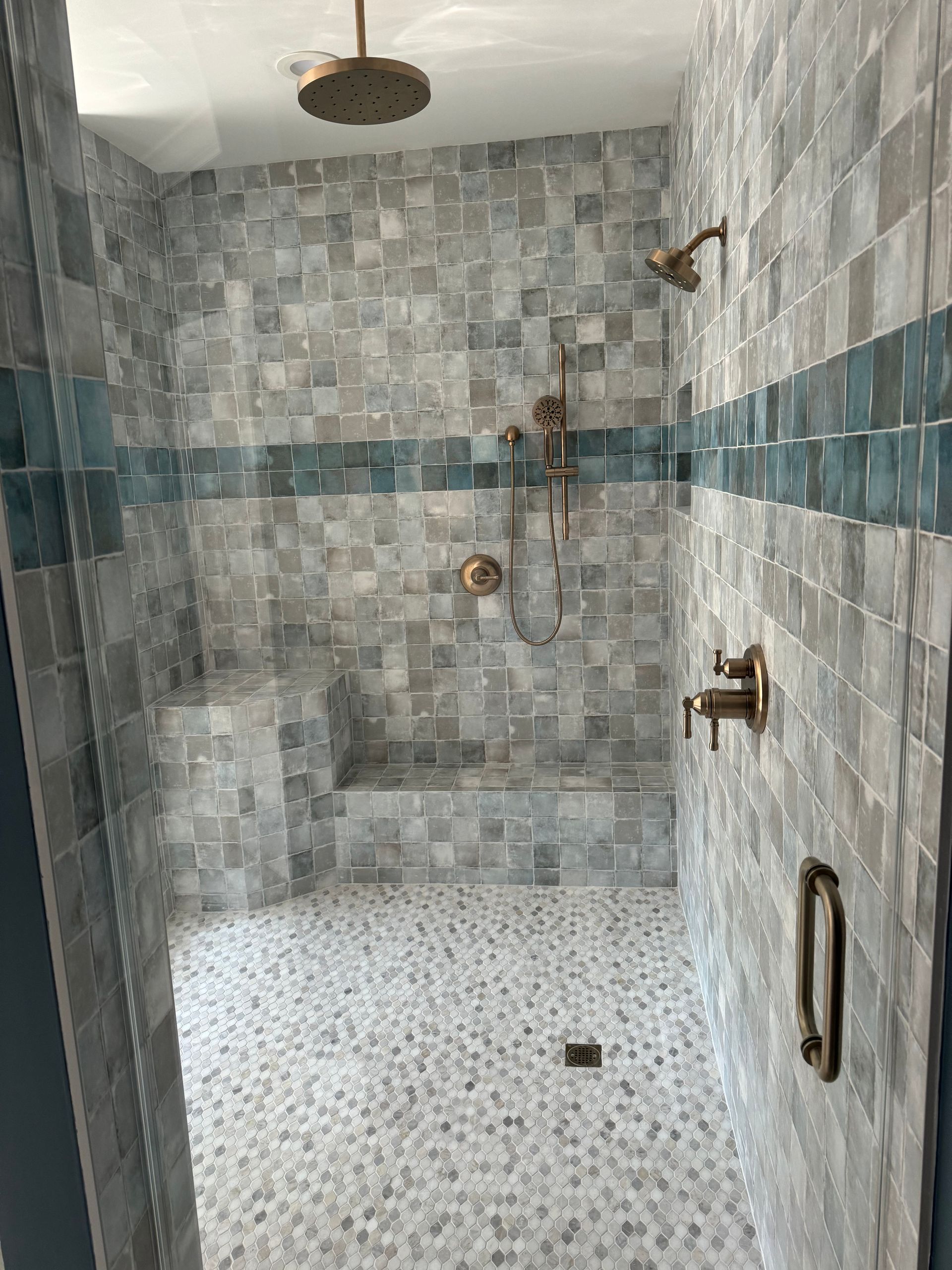 A bathroom with a walk in shower and a bench.