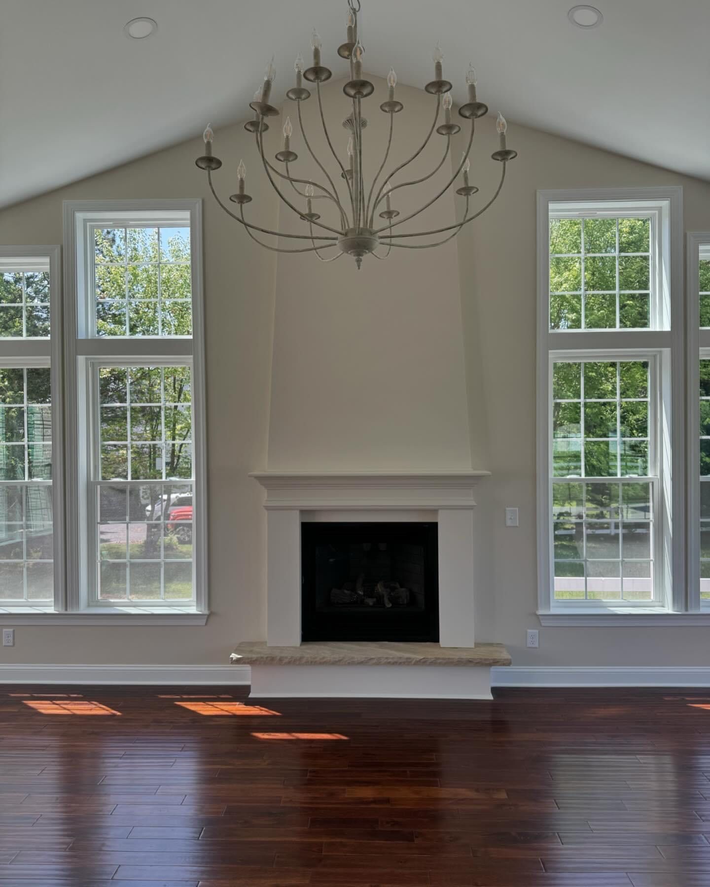 An empty living room with a fireplace and a chandelier