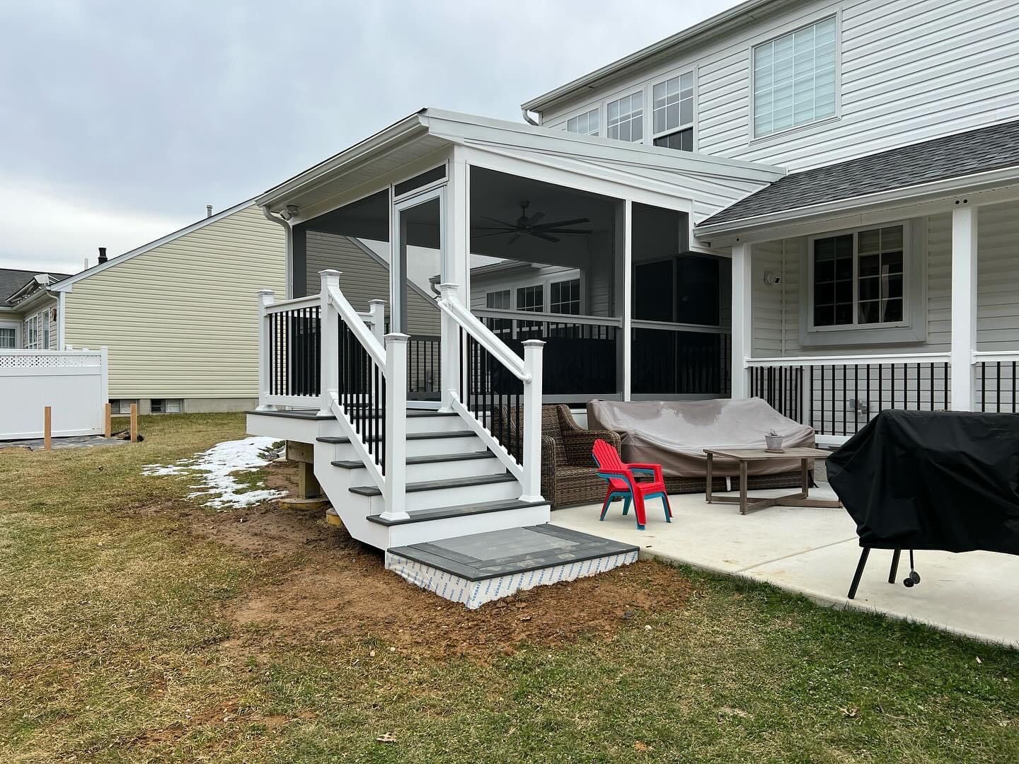 A screened in porch with stairs and a grill in the backyard of a house.