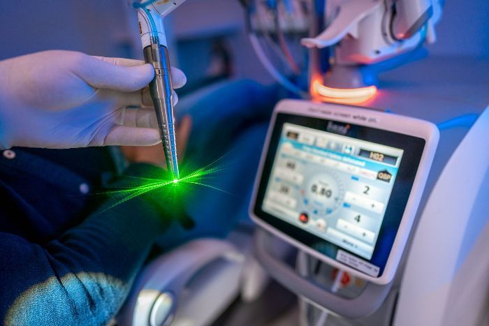 A person is using a machine with a green light coming out of it.