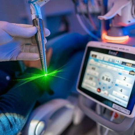 A person is holding a laser in their hand in front of a monitor.