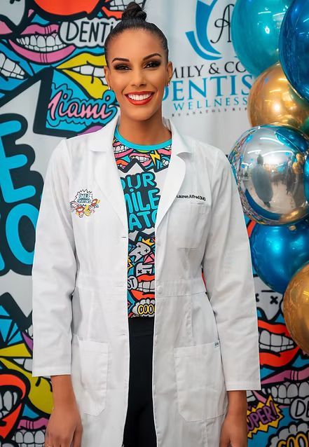 A woman in scrubs is standing in front of a wall with speech bubbles on it.