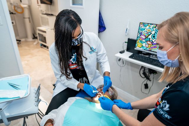 A dentist is examining a child 's teeth in a dental office.