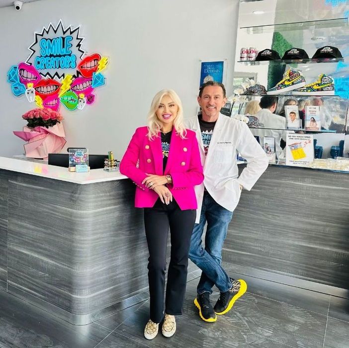 A man and a woman are standing next to each other wearing shirts that say `` your smile creator ''.