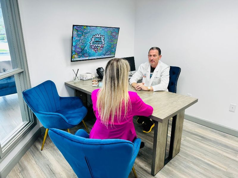 A woman is laying in a dental chair while a dentist examines her teeth.