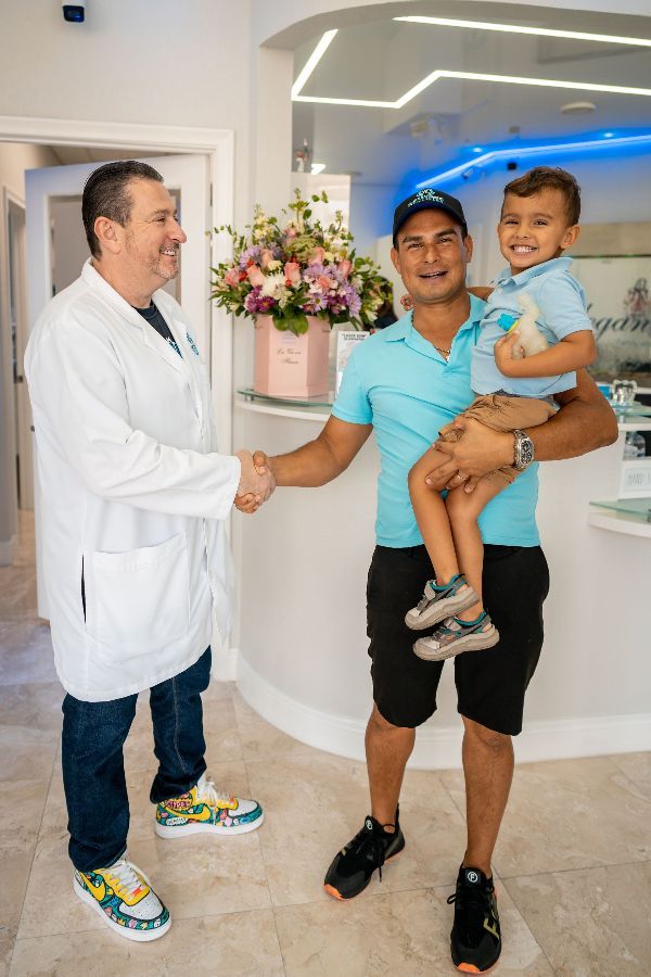 A man is holding a child and shaking hands with a doctor.