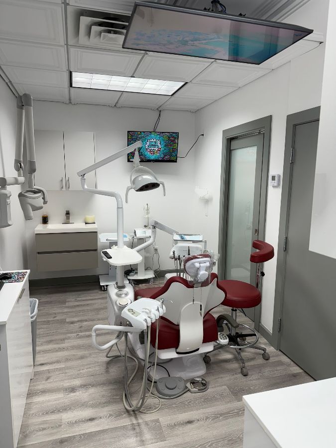 A dental office with a dental chair and a television on the wall.