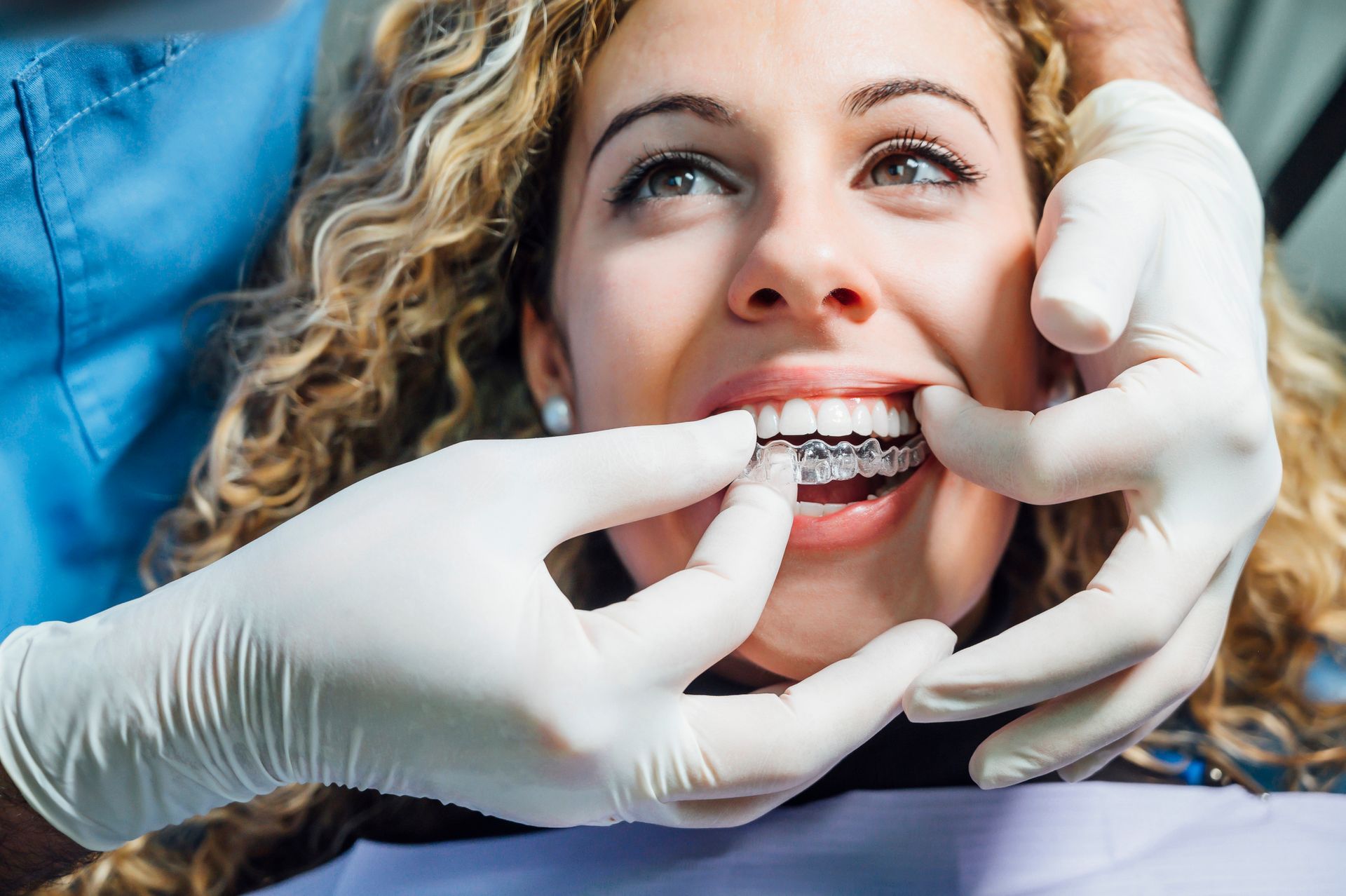 Woman getting Invisalign aligners fitted by a dentist in a dental office.