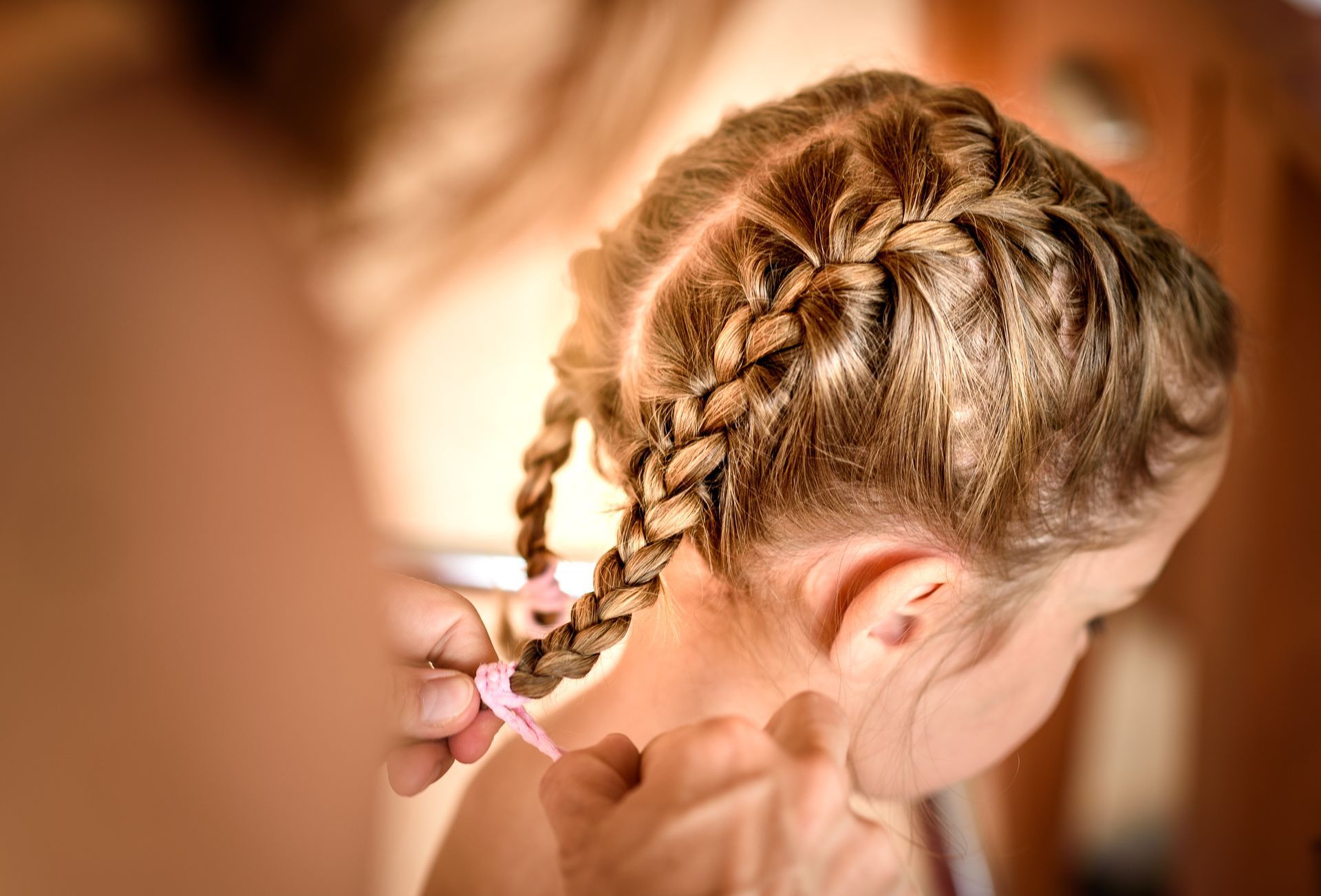 Braided summer hairstyle for kids on a young child with blonde hair and pink hair tie 