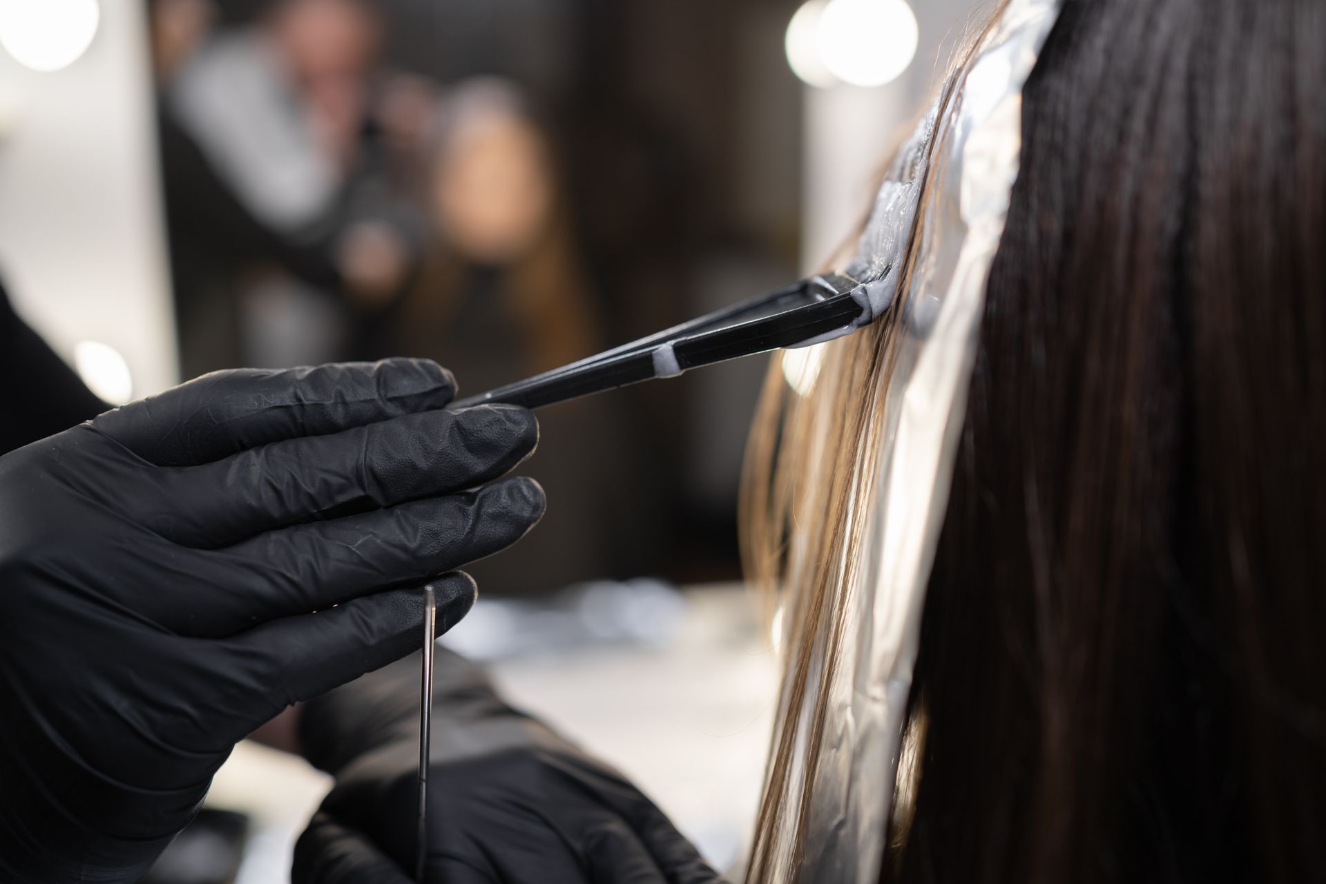 Hairstylist adding highlights to a brunette with straight hair