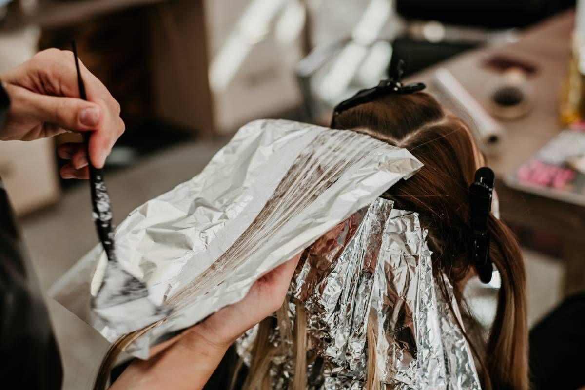 A hair colorist applying foils to a client's hair near Lexington, Kentucky (KY)