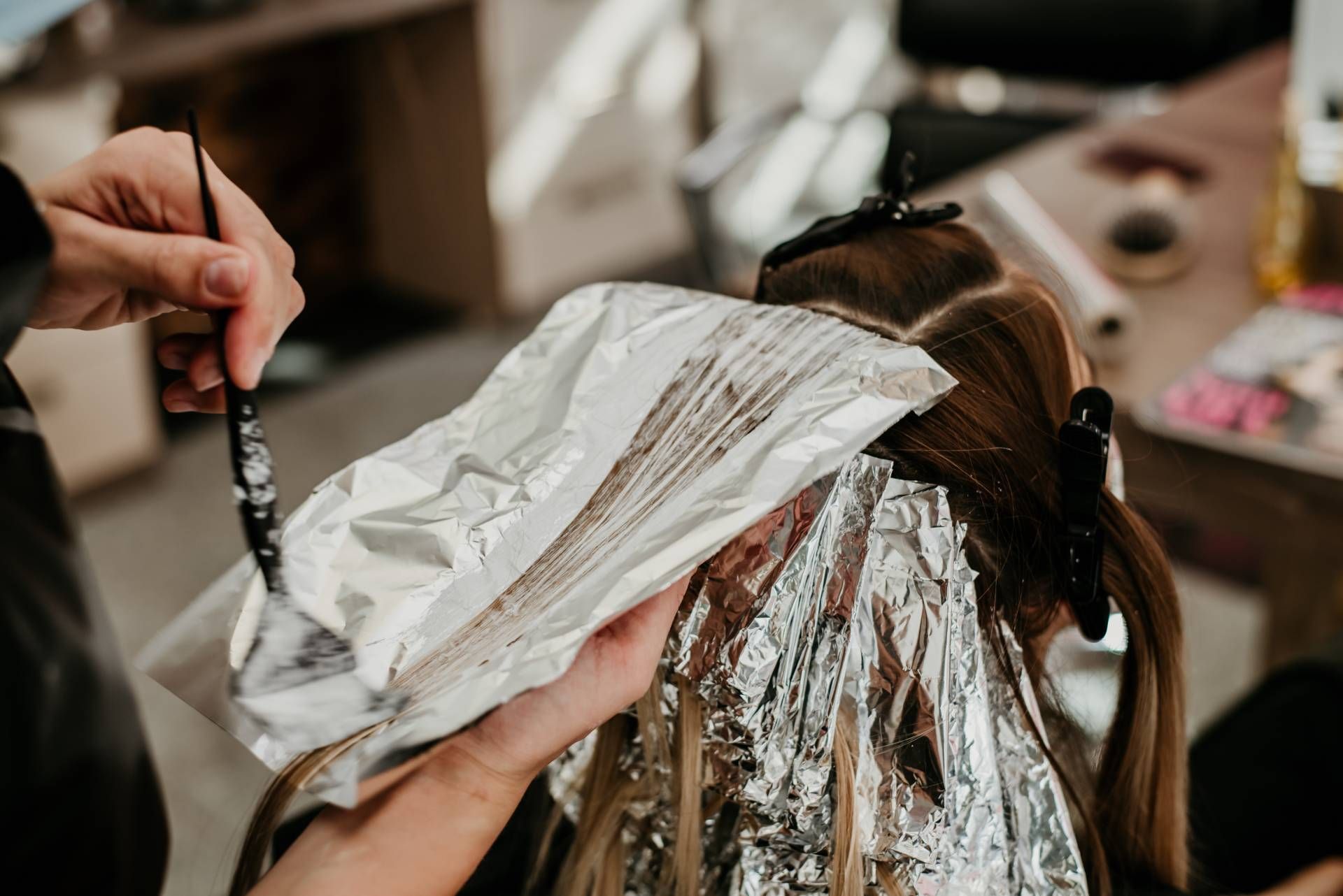 A hair colorist applying foils to a client's hair near Lexington, Kentucky (KY)