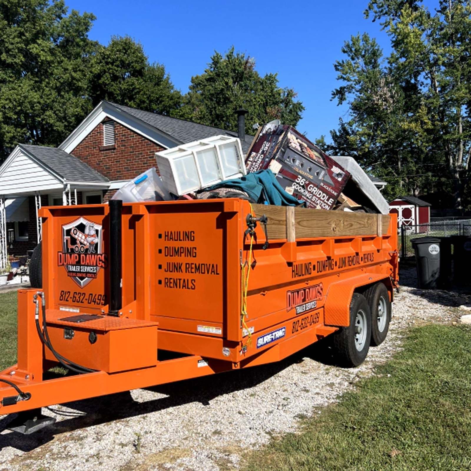 An orange dumpster is full of junk in front of a house