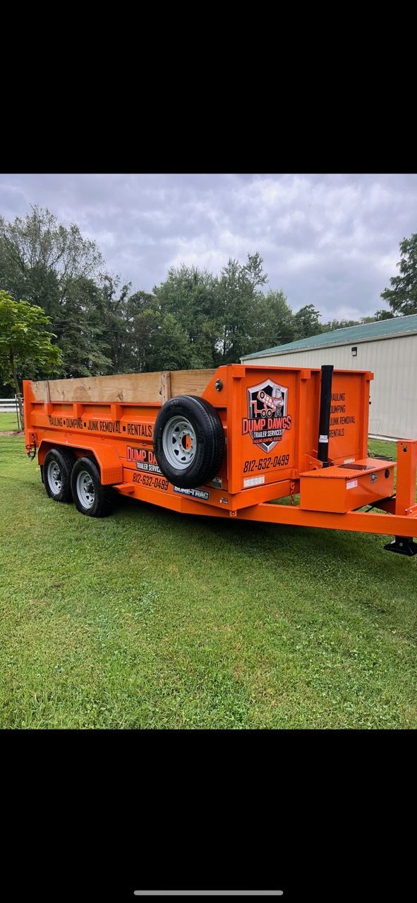 An orange dumpster trailer is parked in a grassy field.