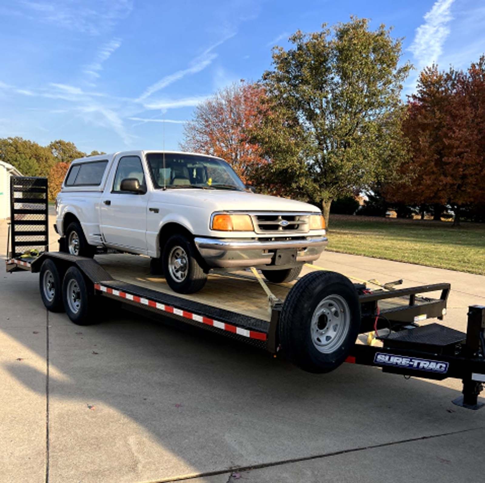 A white truck is sitting on top of a trailer.