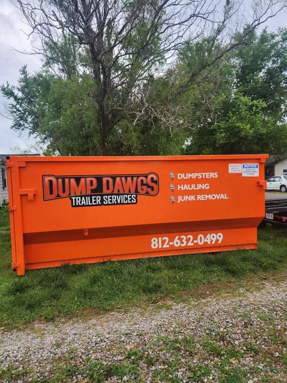 A large orange dumpster is parked in a grassy field.