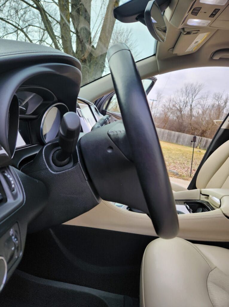 Interior car view: steering wheel, dashboard, driver's seat, and an outside view.