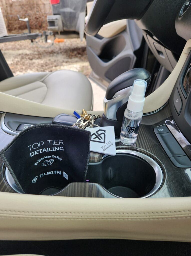 A car's console with a mask, keys, hand sanitizer, and cup holders.