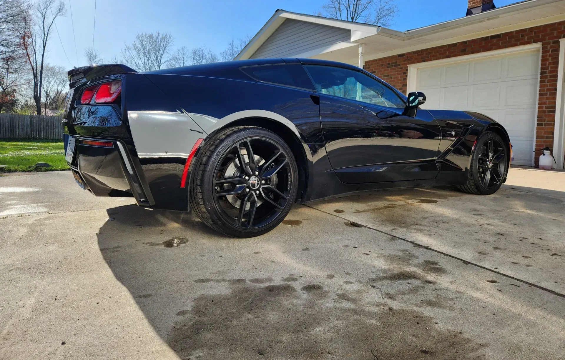 Black Corvette sports car parked outside a garage on a sunny day.