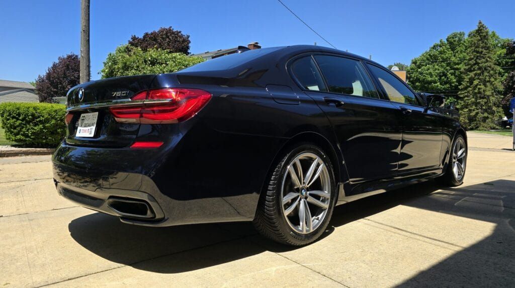 Dark blue BMW sedan parked on a sunny day, with its rear visible.