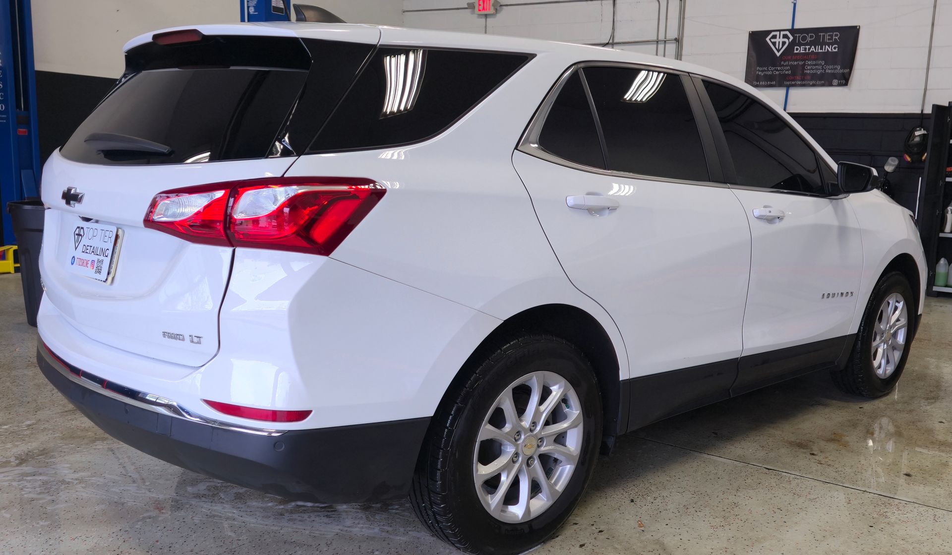 White Chevy Equinox SUV with tinted windows in a garage setting.