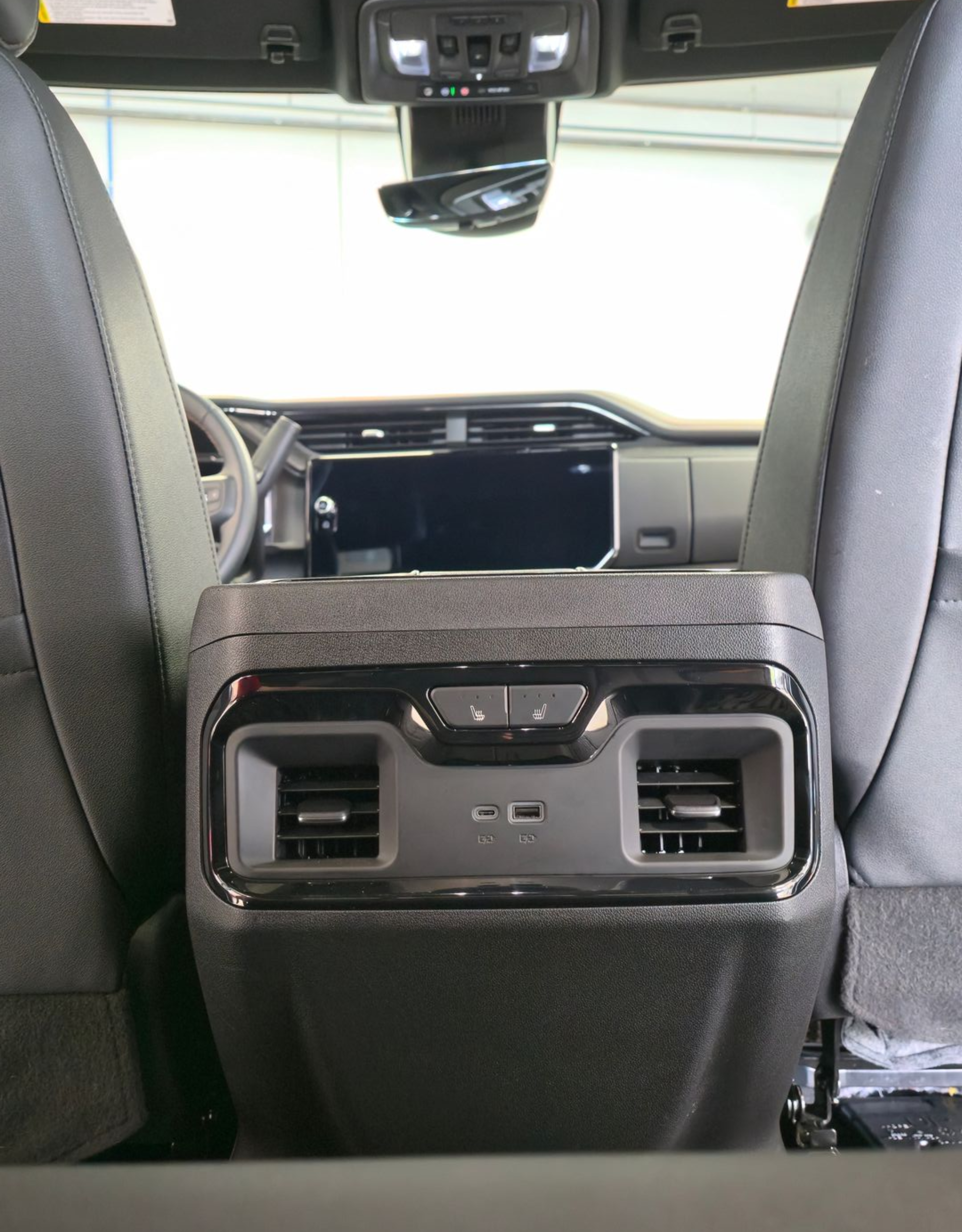 A blue SUV with the back door open, revealing the folded-down back seat and cargo area.