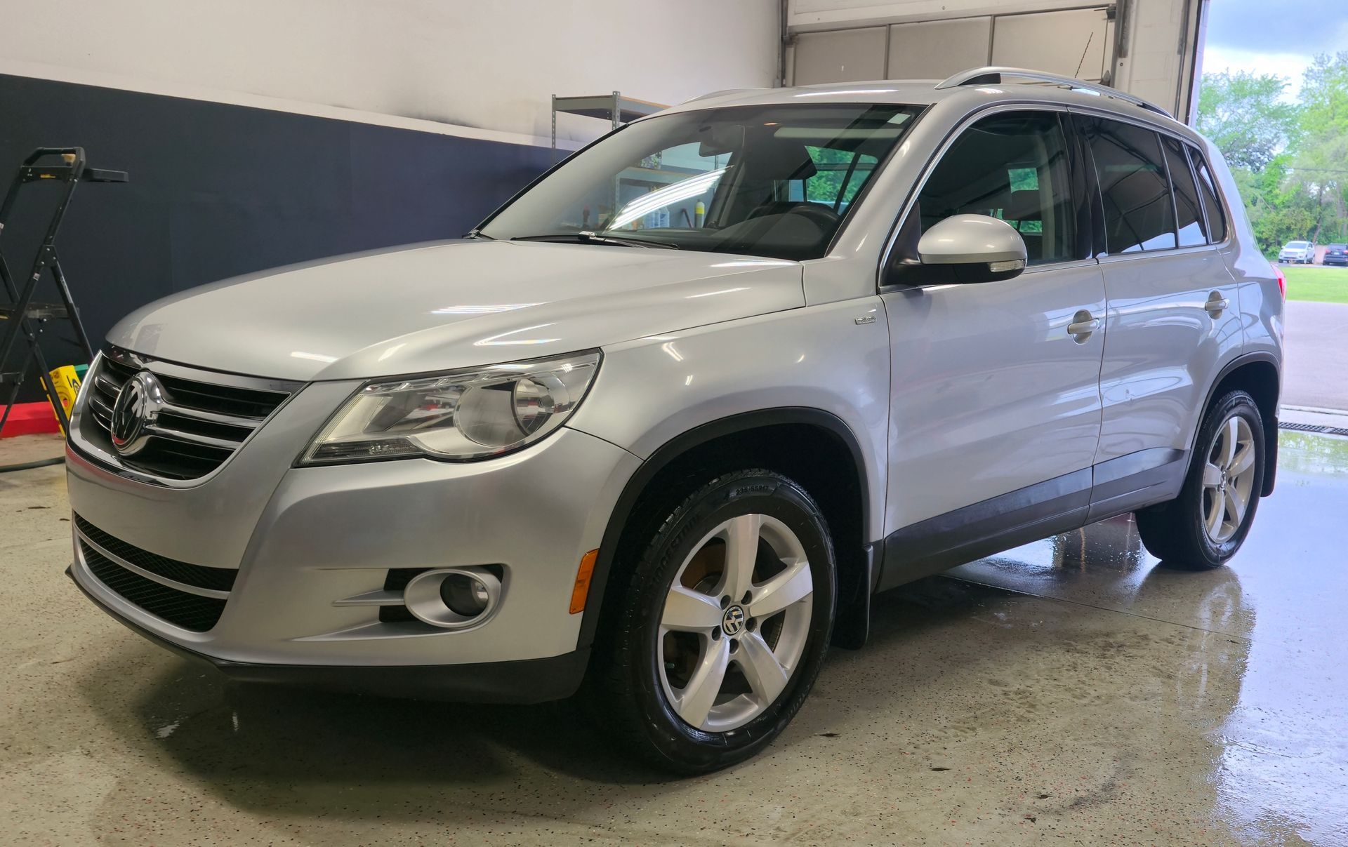 Silver Volkswagen Tiguan SUV parked inside a garage, angled view, cloudy day.