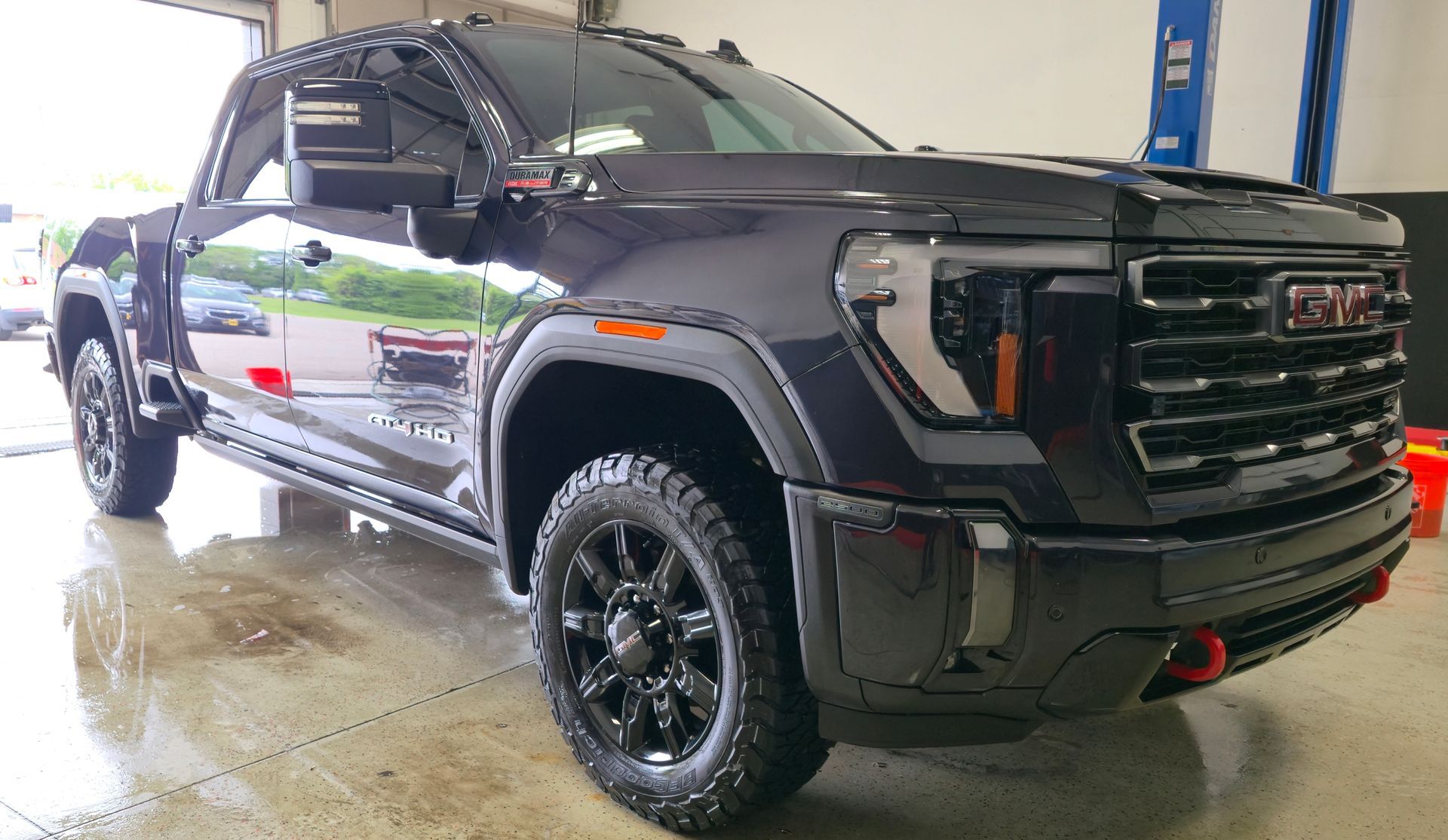 Black Ford F-150 pickup truck, parked inside a garage. Black wheels and trim.