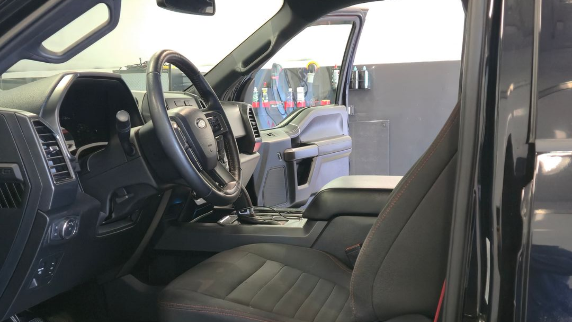 Interior view of a black truck cab; seat, steering wheel, dashboard visible.