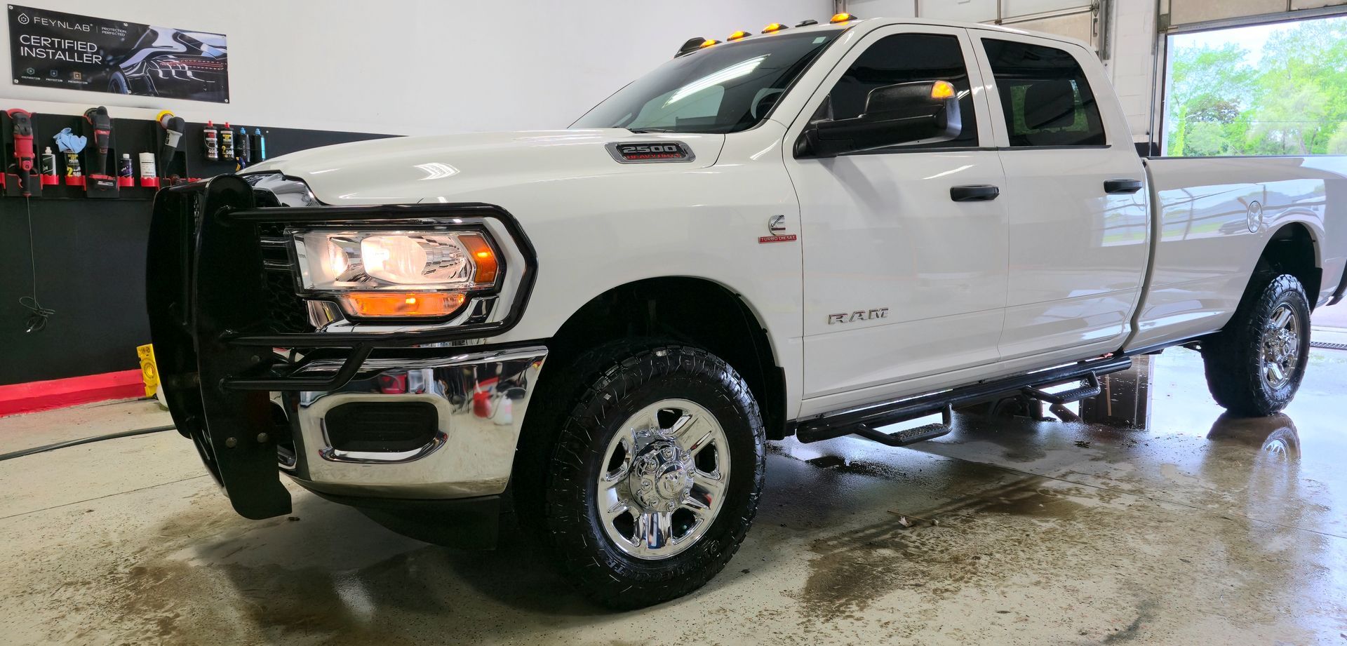 White Ram pickup truck with a black grill guard parked inside a garage.